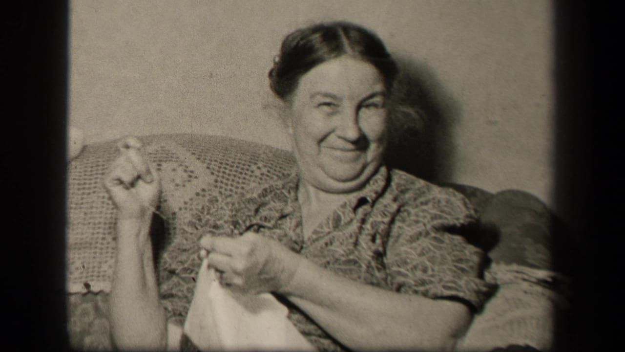 The woman smiles toward the camera with sewing in her lap, seated in a private Sebring, Ohio home interior in 1942.