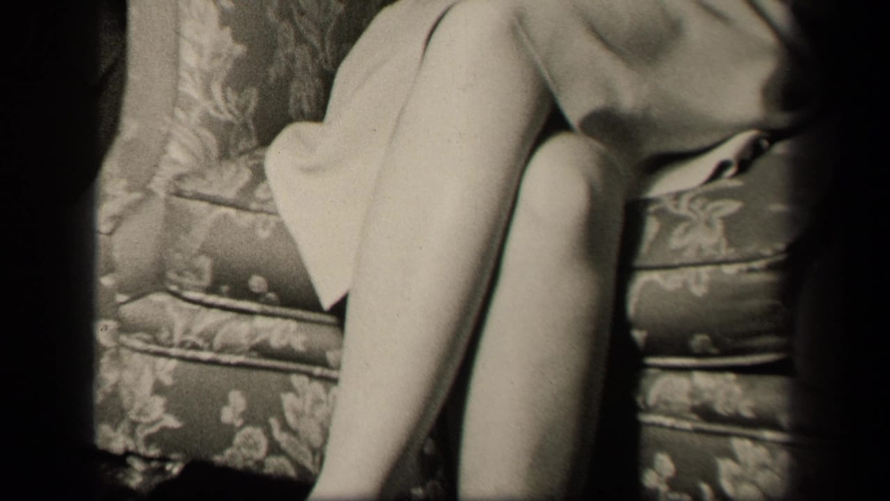 1942 Sebring, Ohio frame with the woman's crossed legs and dress hem against patterned couch cushions in a private interior.