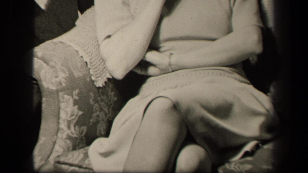 Adult woman seated in an upholstered chair, cropped from shoulders to knees.