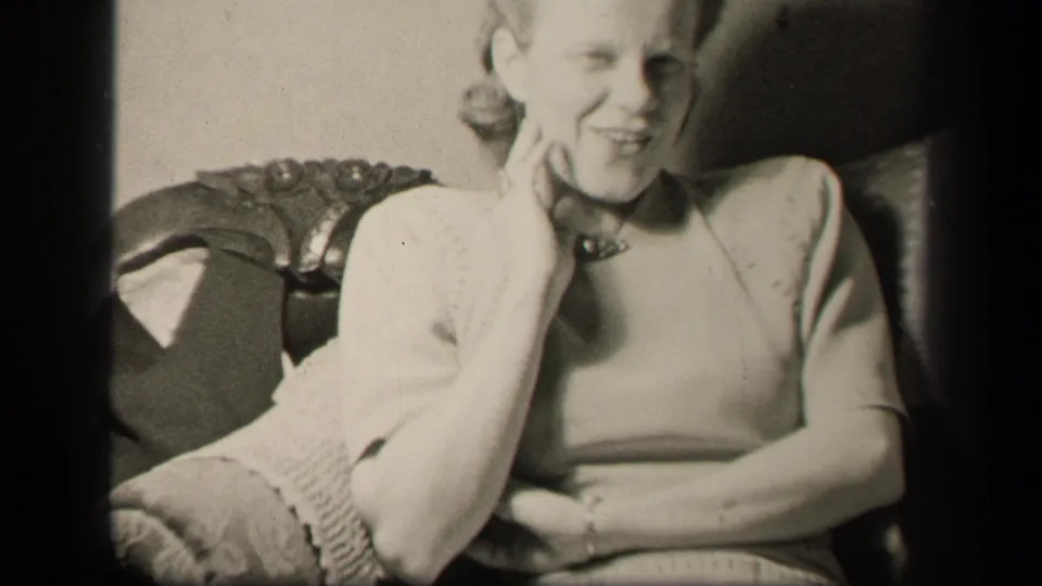 The woman smiles toward the camera while seated in an ornate armchair in 1942 Sebring, Ohio home-movie footage.