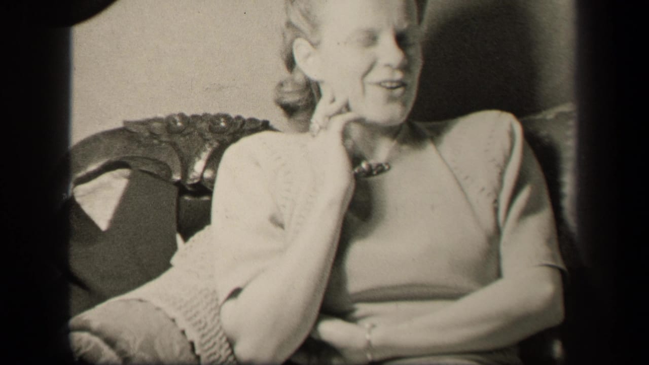 Adult woman in a light dress smiles while seated in an ornate chair.