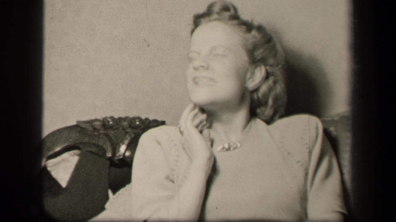 In 1942 Sebring, Ohio home-movie footage, a woman in a light dress sits in an ornate chair, eyes partly closed, hand raised near her neck.