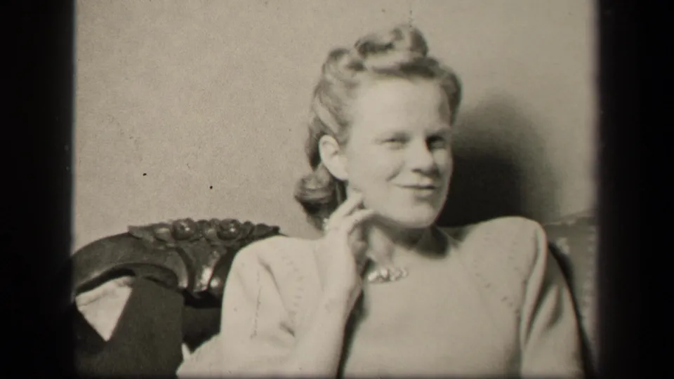 In 1942 Sebring, Ohio home-movie footage, the seated woman smiles toward the camera while resting her hand near her neck.
