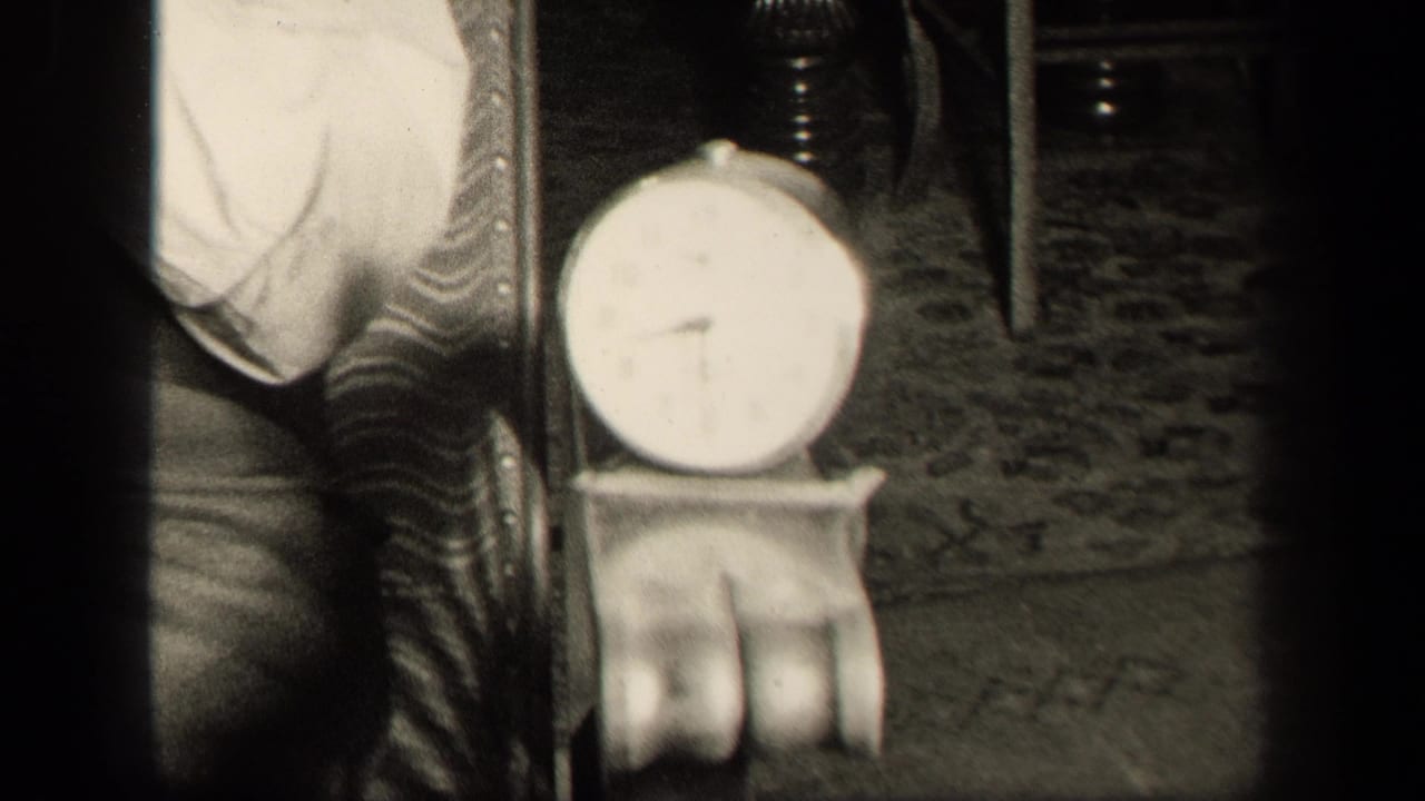 1942 Sebring, Ohio home-movie frame showing a small round clock near a patterned chair inside a private room.