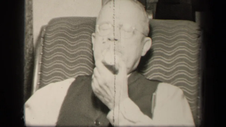 Older gentleman in glasses and vest sits in a wavy-pattern chair in Sebring, Ohio, bringing fruit to his mouth.