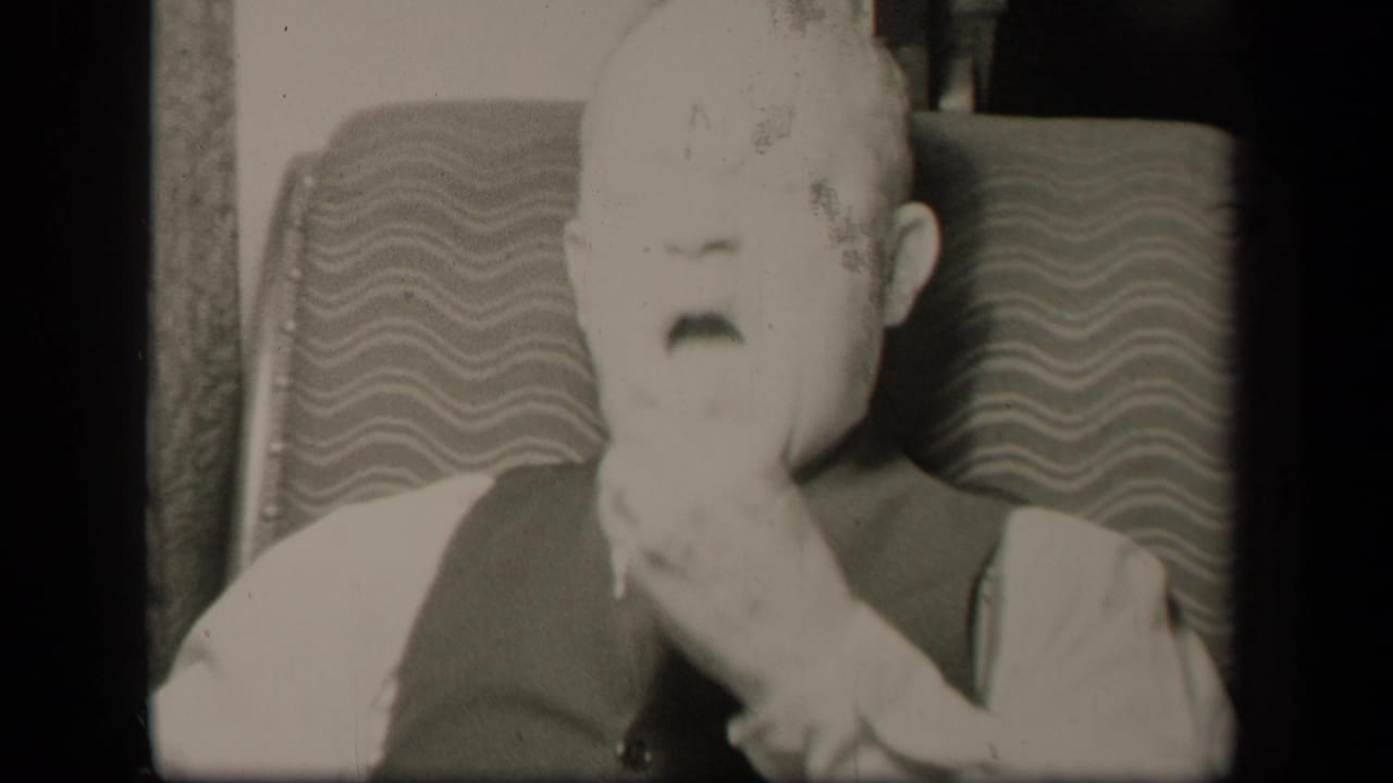The seated elderly man in Sebring, Ohio appears to bring his hand to his mouth while framed closely against the patterned chair.