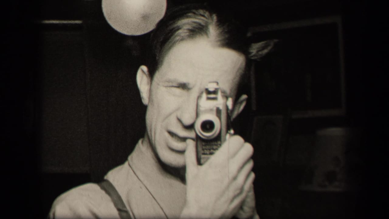 In a 1942 Sebring, Ohio home-movie frame, a man films his reflection with a compact camera beneath a globe lamp.