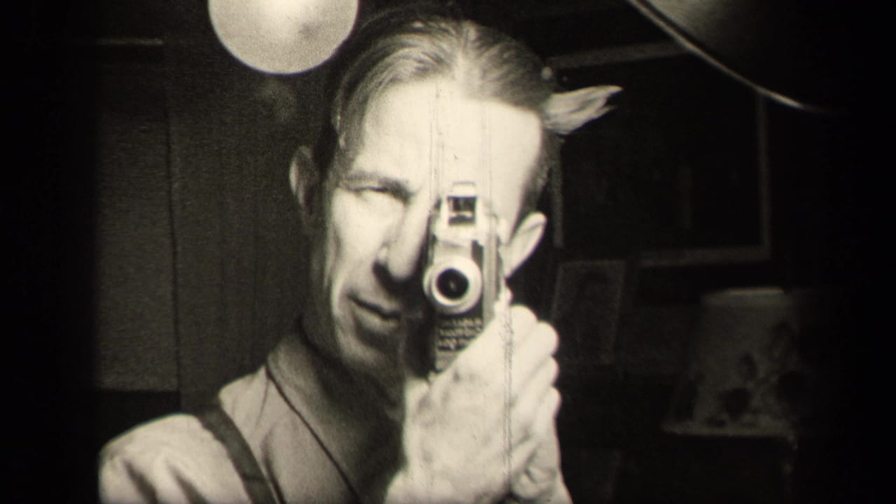 In Sebring, Ohio 1942 home-movie footage, a man in suspenders peers through a small camera in a dark interior.