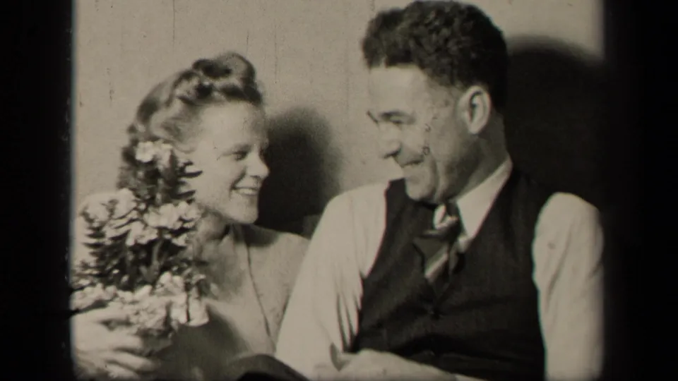 In 1942 Sebring, Ohio home-movie footage, a young woman with flowers smiles toward a young man in a vest and tie.