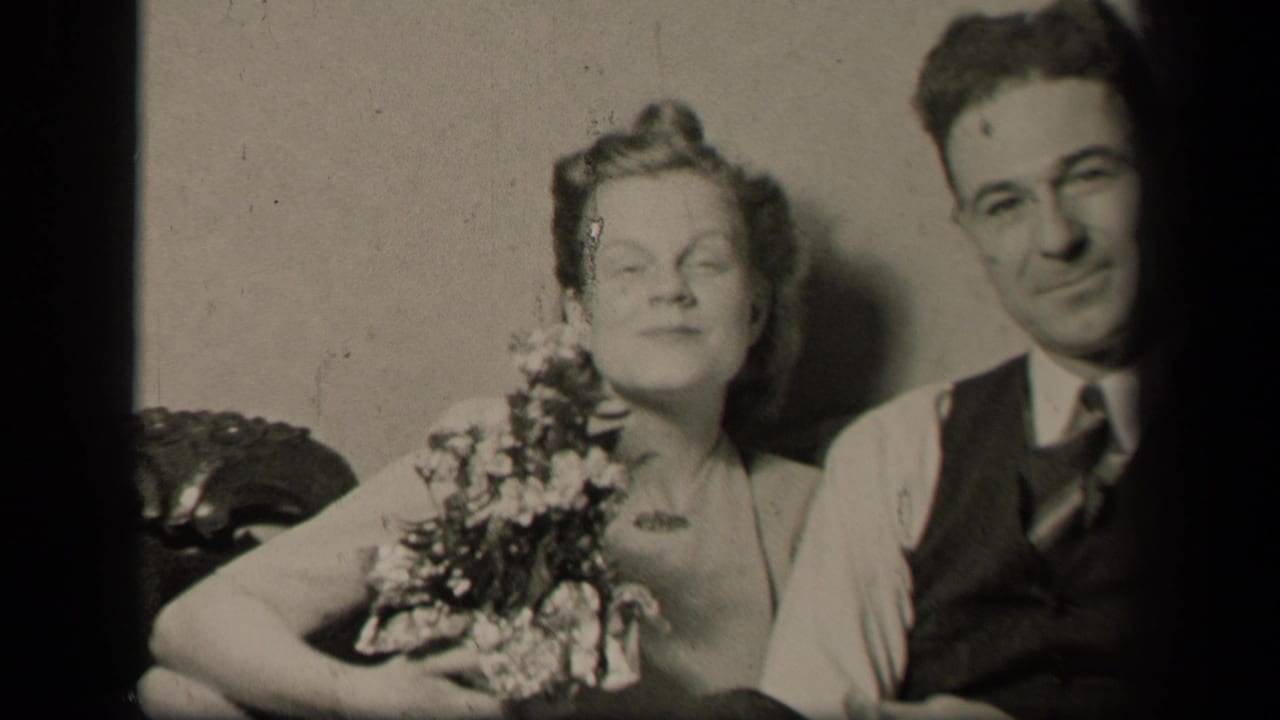 In metadata-supported Sebring, Ohio, 1942, a woman with flowers sits close to a man in a vest and tie on a sofa.