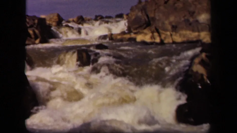 1943 Maryland home-movie frame, per metadata, showing water cascading past dark boulders and rocky ledges.