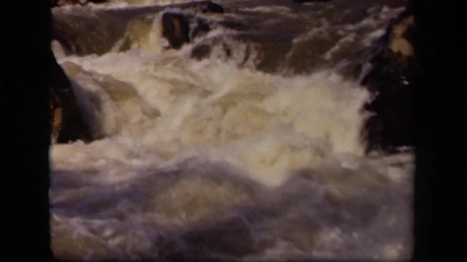 A 1943 8mm home-movie frame shows churning river foam and dark rocks, separated by the contact-sheet film border.