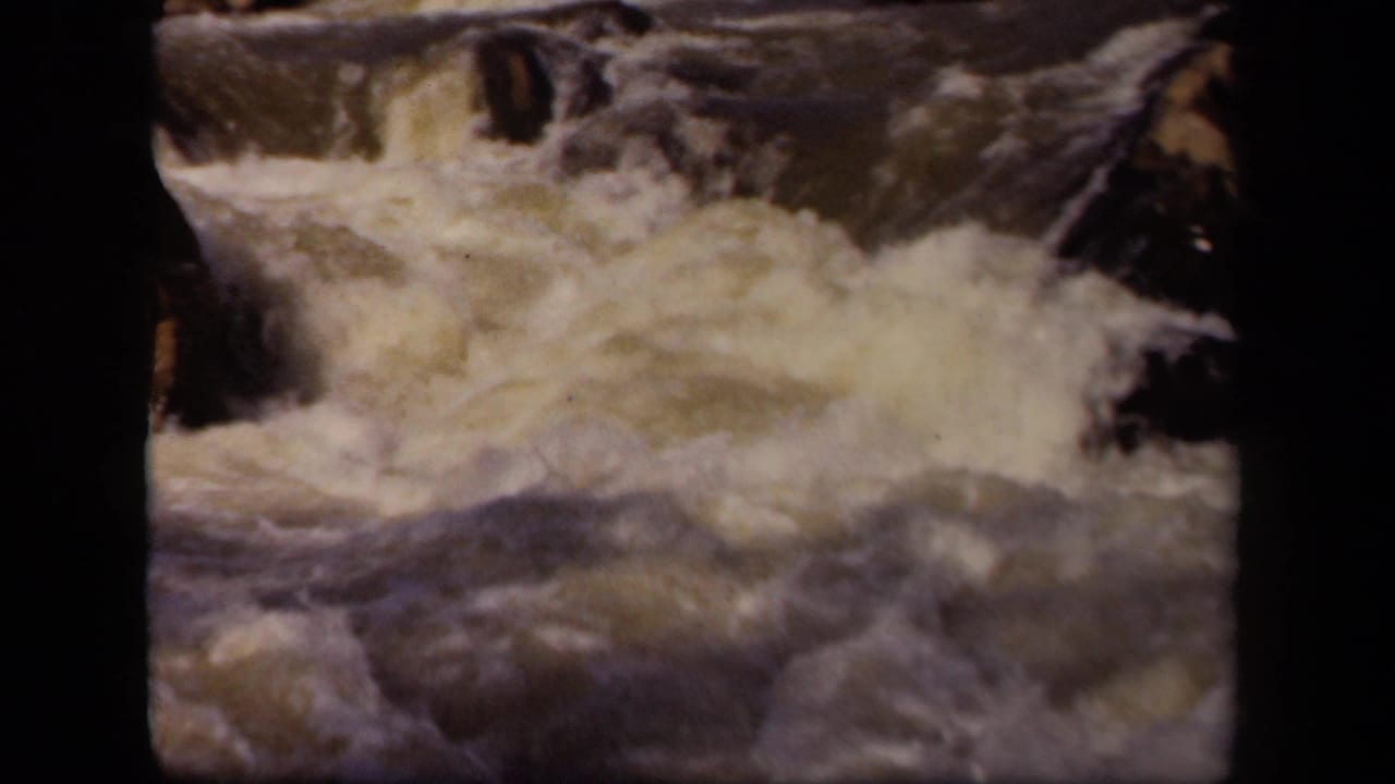 1943 8mm Maryland home-movie frame showing churning white water in a rocky river channel.