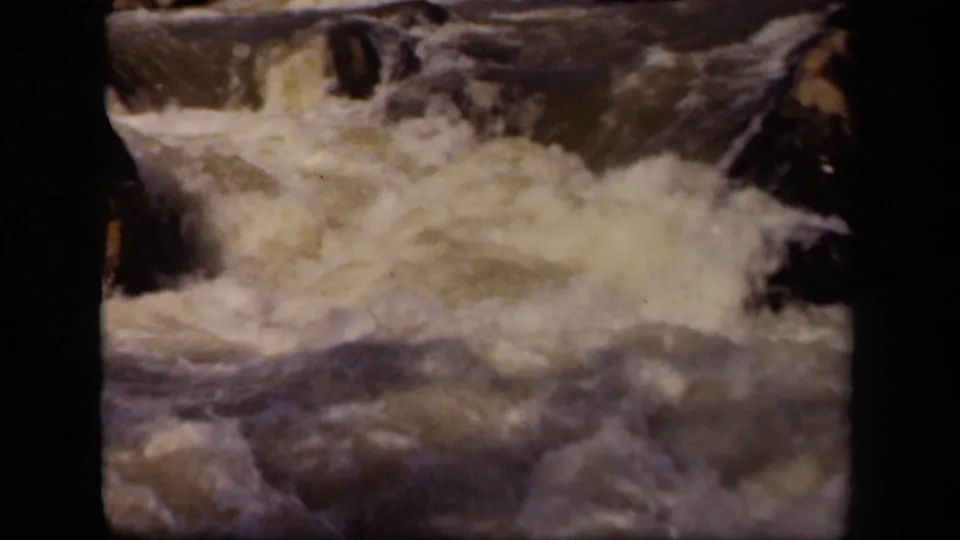 1943 8mm Maryland home-movie frame showing churning white water in a rocky river channel.