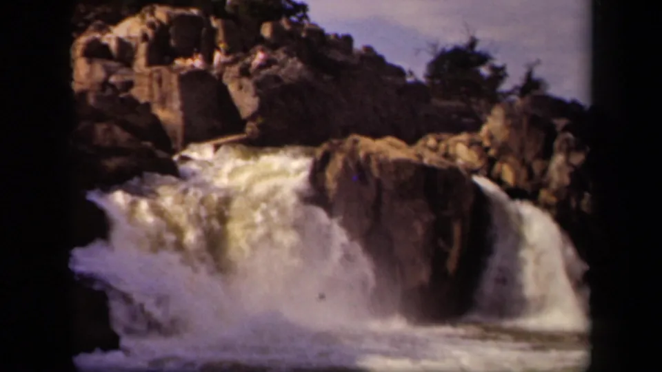 1943 8mm frame from Baltimore, Maryland, showing a waterfall dropping over rugged rocks in bright daylight.