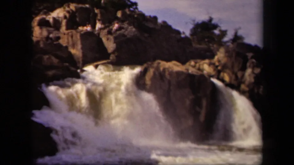Vintage 8mm Maryland waterfall view with white water pouring around jagged rock formations.