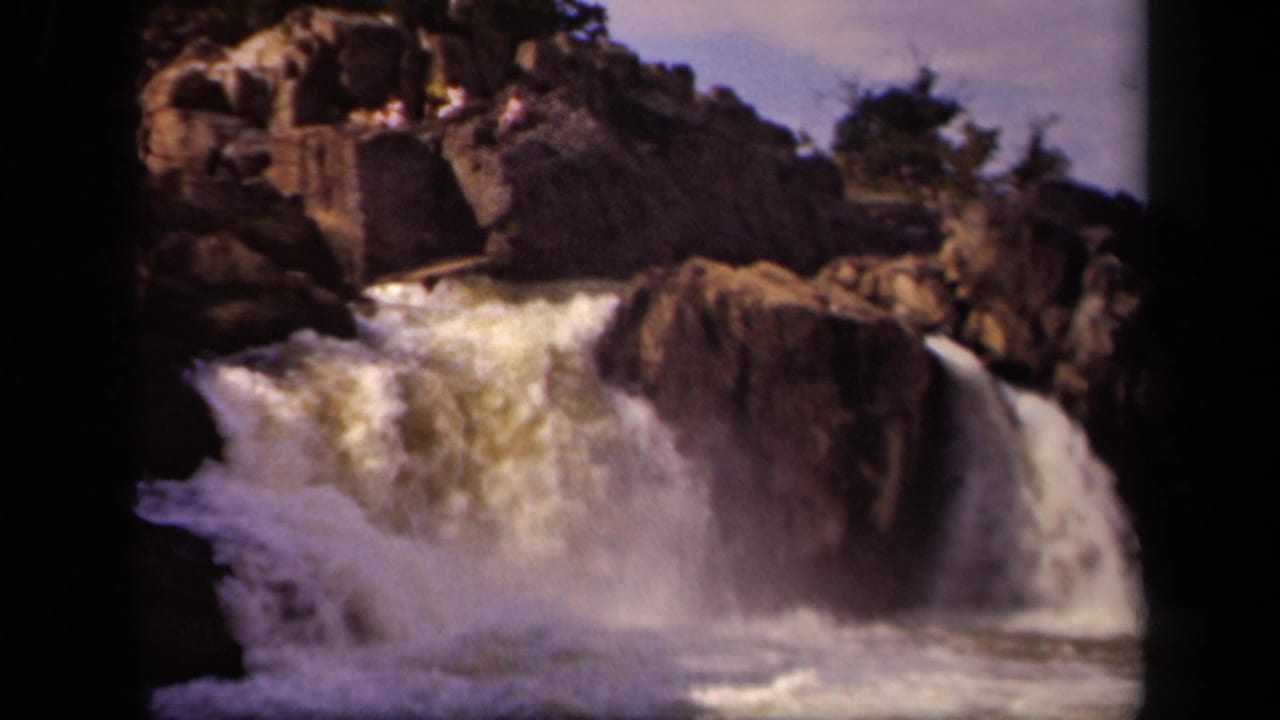 1943 8mm home-movie frame of turbulent whitewater dropping through rocks near Baltimore, Maryland, with soft grain and dark frame edges.