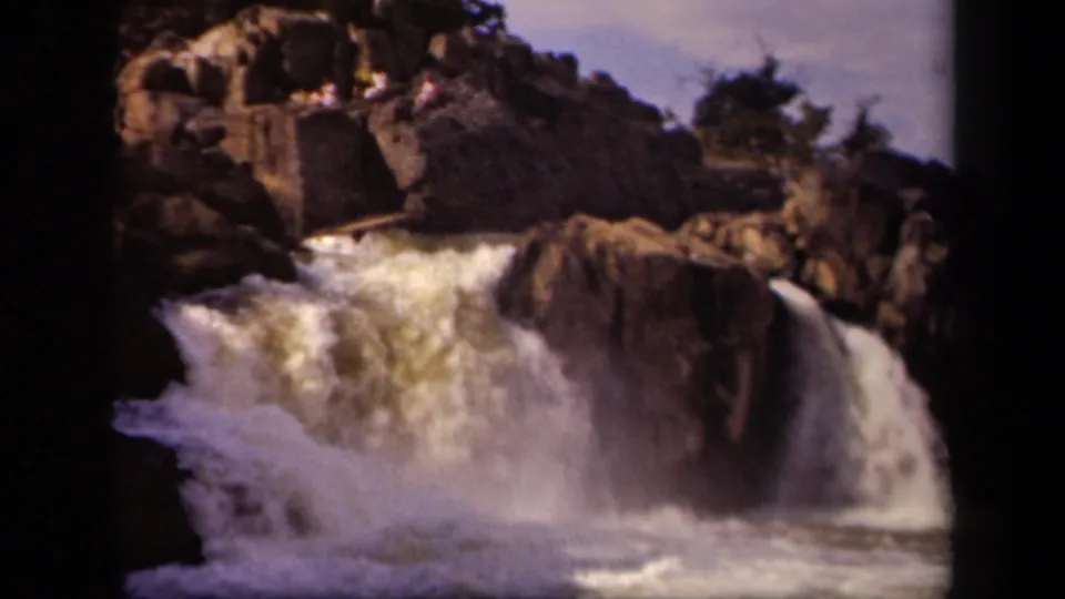 1943 8mm home-movie frame of turbulent whitewater dropping through rocks near Baltimore, Maryland, with soft grain and dark frame edges.