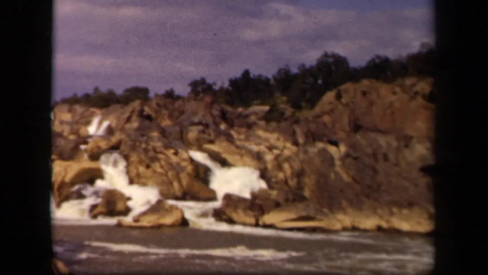 A wide 8mm home-movie frame shows rocky cascades and whitewater beneath trees in the supplied 1943 Baltimore, Maryland clip.