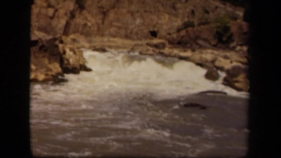 1943 Baltimore home-movie frame of a rocky stream with white water crossing the center of the shot.
