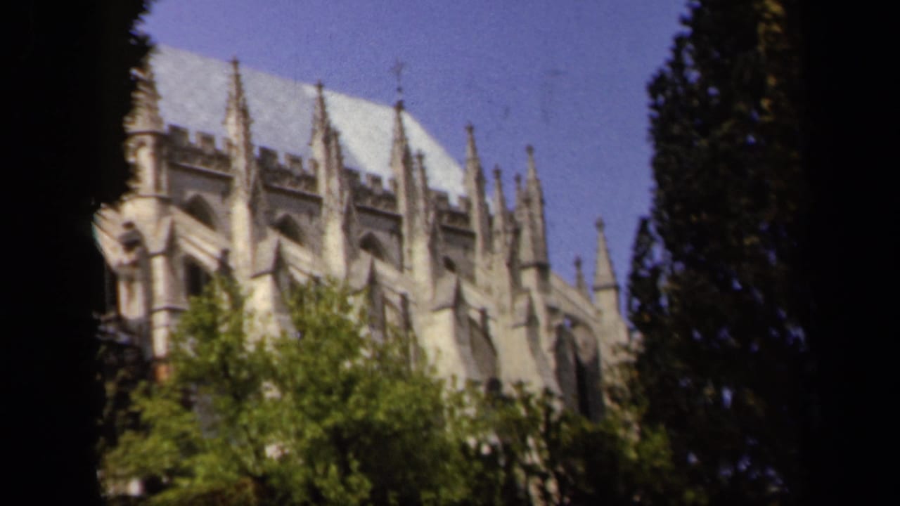 1943 Baltimore 8mm frame showing a Gothic-style stone building partly obscured by trees and foliage.