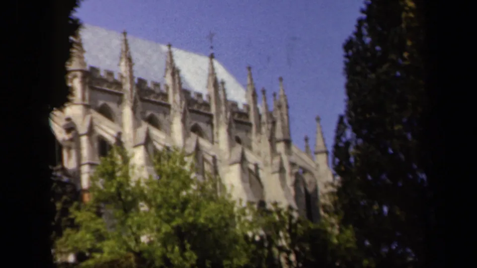 1943 Baltimore 8mm frame showing a Gothic-style stone building partly obscured by trees and foliage.