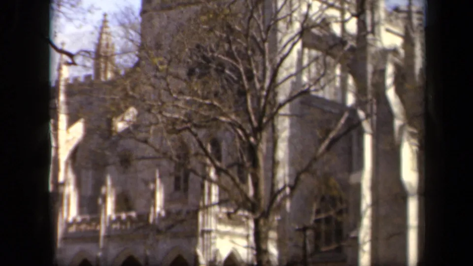 Baltimore 1943 frame with tree branches crossing a Gothic-style stone building, including pointed arches and an upper tower detail.