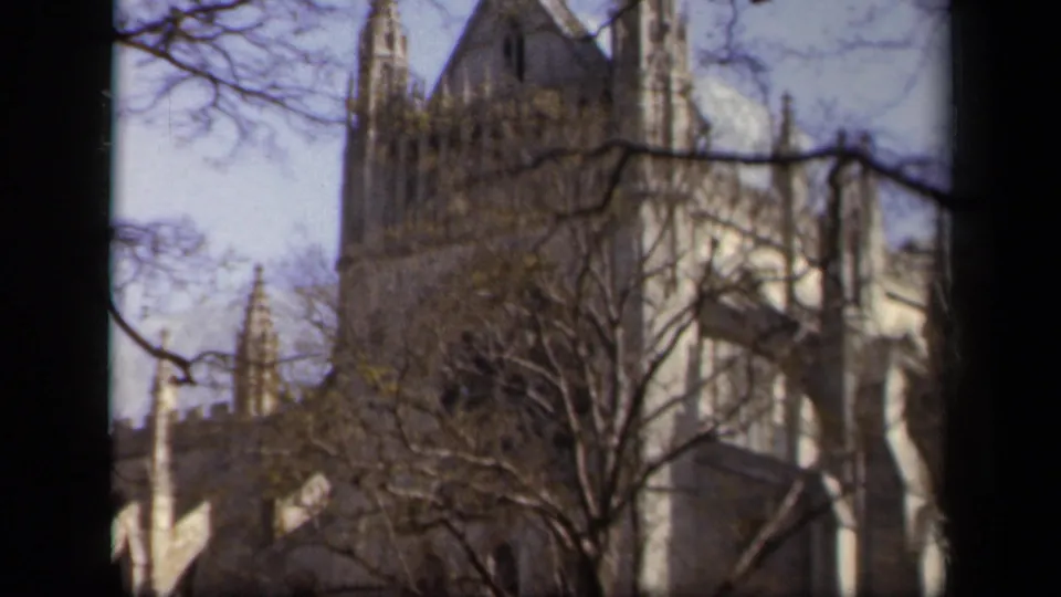 1943 Baltimore home-movie view of a Gothic-style church tower and spires behind leafless trees.