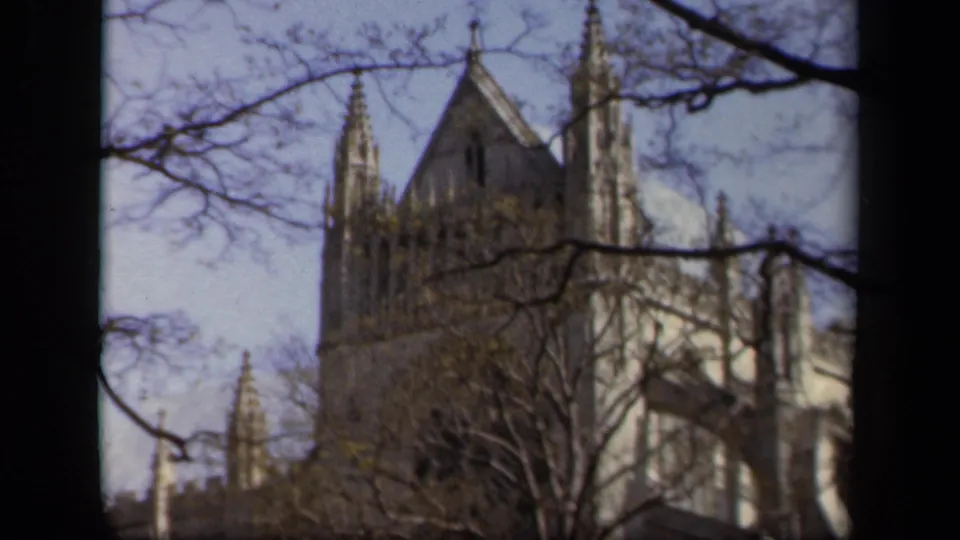 1943 Baltimore frame showing a Gothic-style church roofline and tower through bare branches on 8mm film.