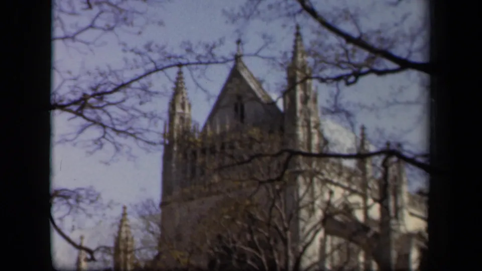 Baltimore cathedral exterior in soft 8mm color, with spires partly obscured by leafless branches.