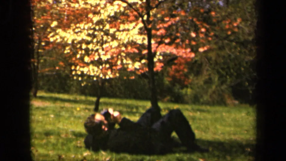 At Skyline Drive in 1943, a person lies on the grass with a camera beneath orange and yellow autumn trees.