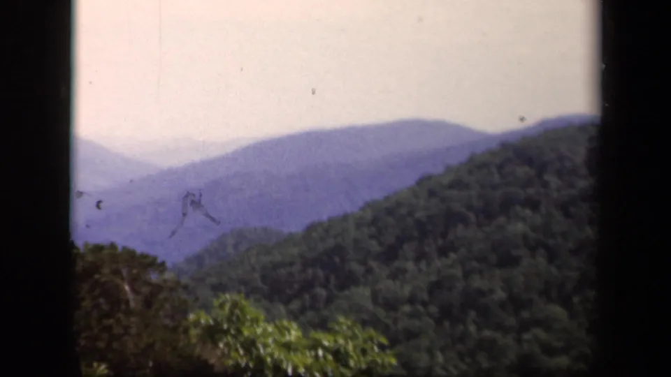 Skyline Drive, Virginia home-movie frame showing hazy blue ridges and forested foreground hills on 8mm film.
