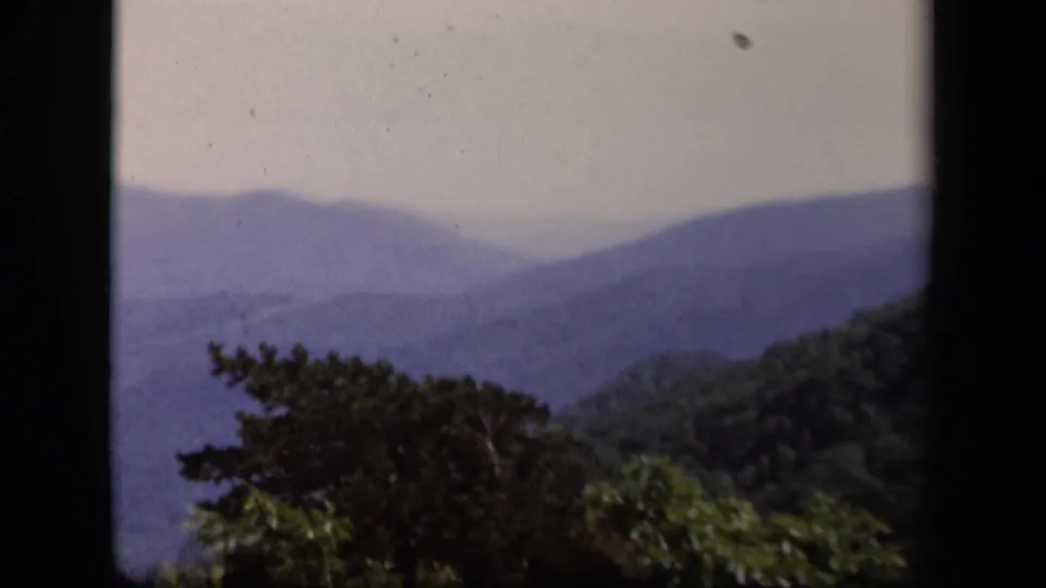 1940s 8mm travel footage frame of a Skyline Drive mountain overlook with trees and hazy ridgelines.