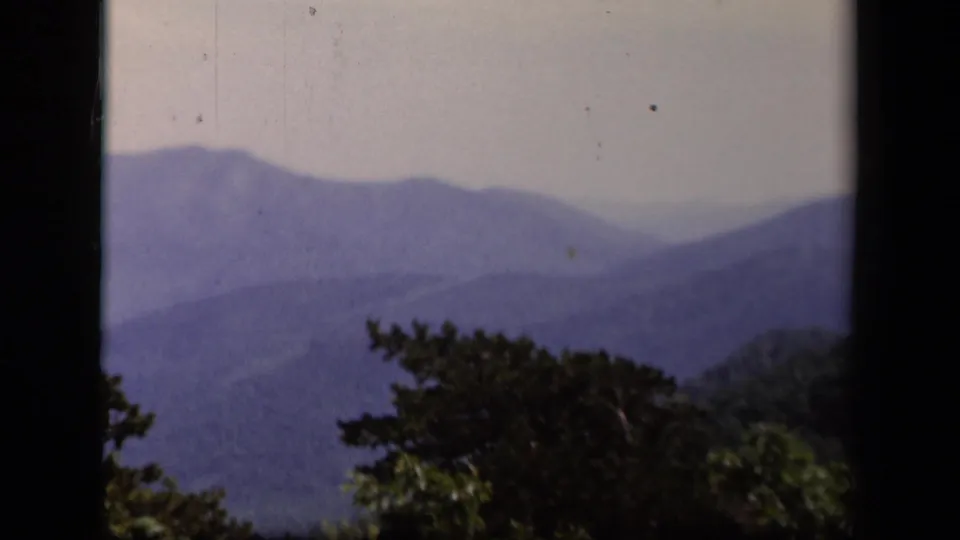 1943 Virginia mountain panorama with layered ridges, foreground foliage, and small 8mm film marks.