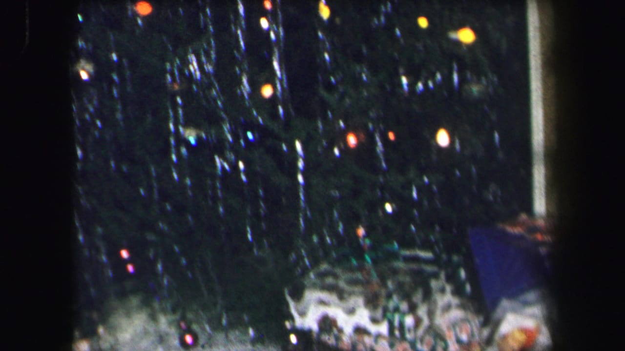 Tinsel-covered Christmas tree with lights and presents at the edge.