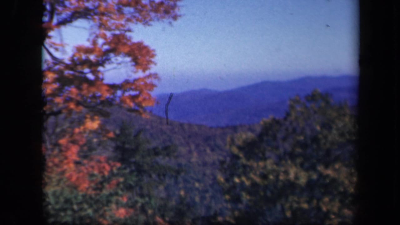 Blue mountain ridges and autumn-colored trees fill a soft 8mm landscape frame.