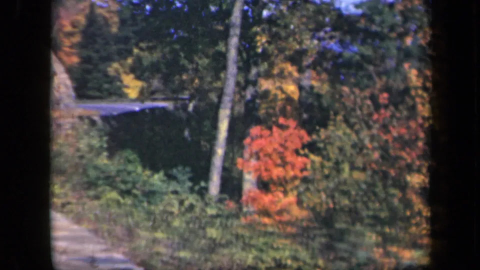 1943 Skyline Drive footage shows a curved mountain road bordered by stonework, rocky slope, and red-orange fall foliage.