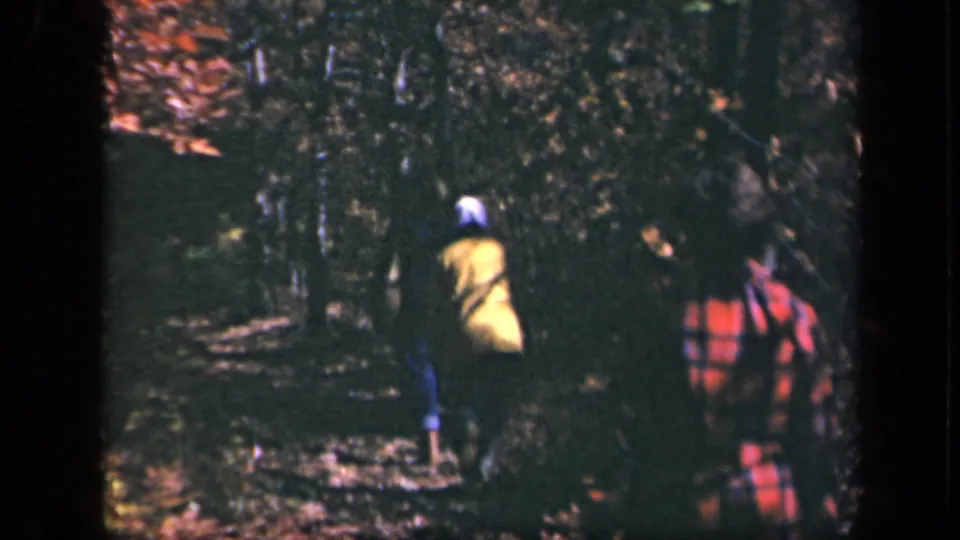 1943 Skyline Drive frame showing multiple walkers on a wooded autumn trail, with yellow and red plaid clothing visible.