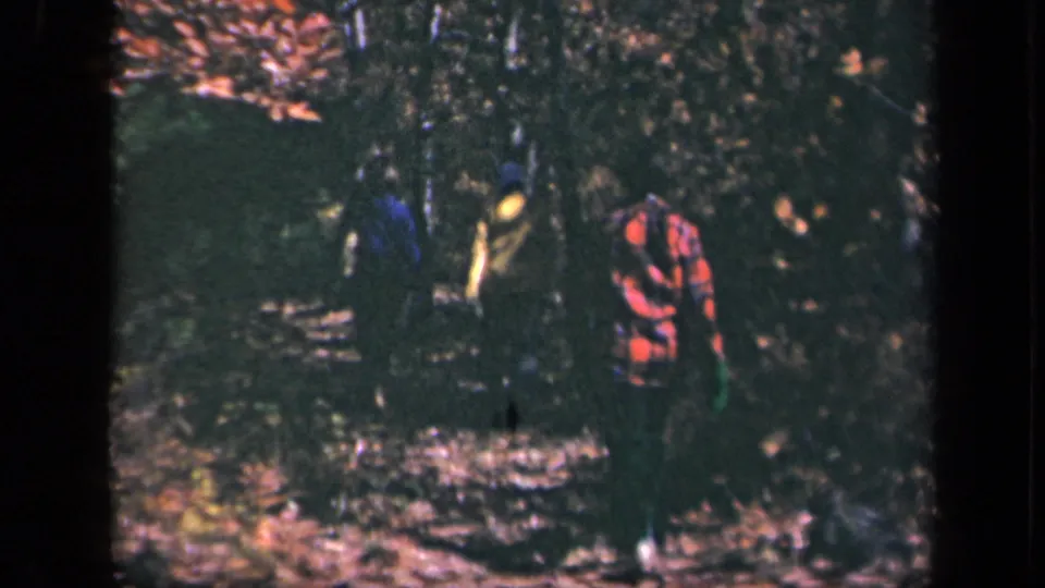 A 1940s home-movie view of hikers on Skyline Drive, with the red plaid figure closest and others partly obscured by shade.
