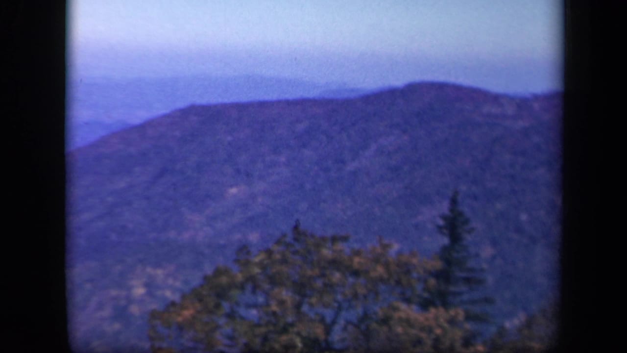 1943 Skyline Drive view of a hazy mountain ridge with winter trees and dark 8mm frame edges.