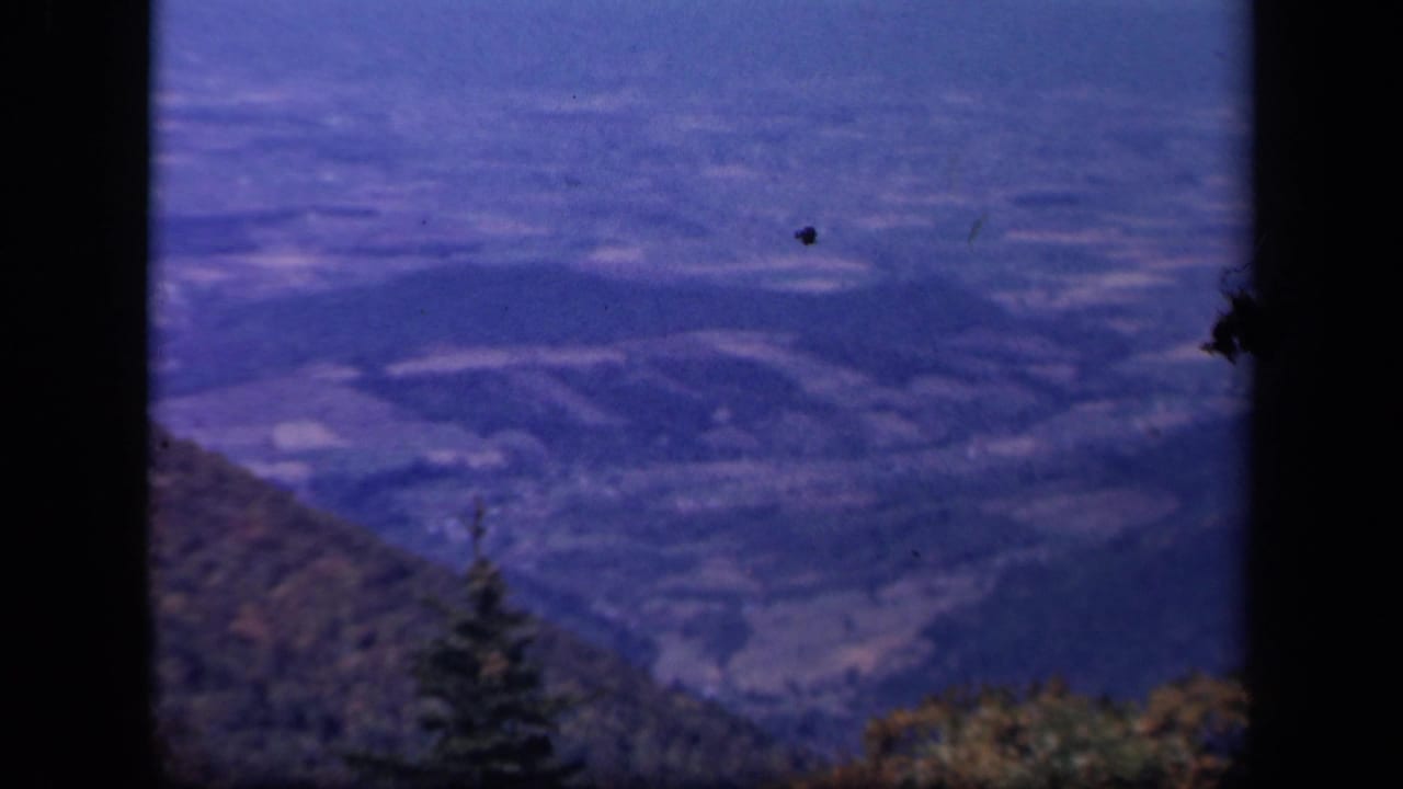 Skyline Drive, Virginia landscape with blue-toned hills, valley fields, and trees visible through an 8mm frame.