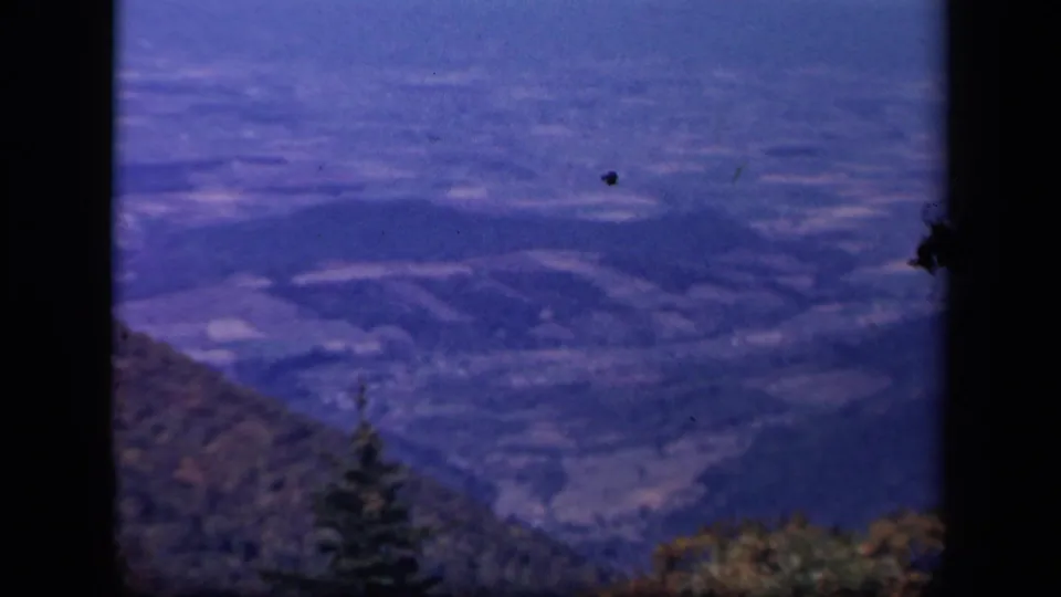 Skyline Drive, Virginia landscape with blue-toned hills, valley fields, and trees visible through an 8mm frame.