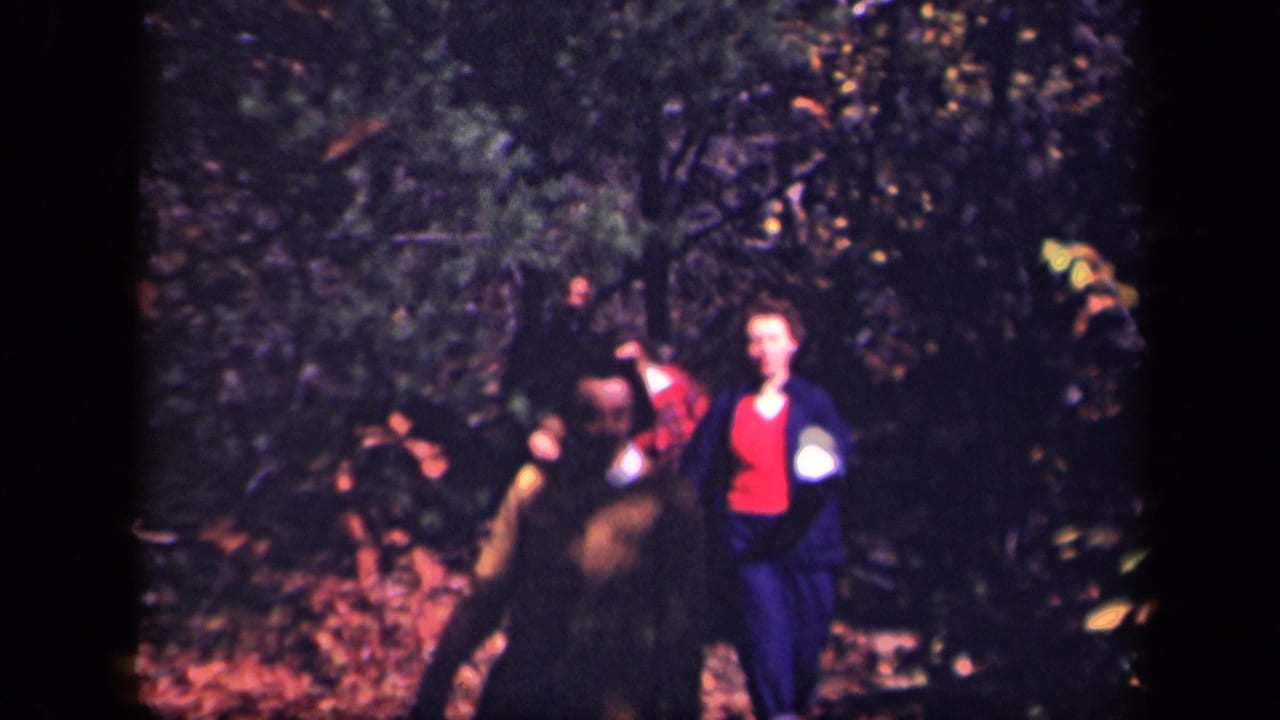 1943 Skyline Drive home-movie frame with adults moving along a wooded autumn path as the handheld camera catches them mid-walk.