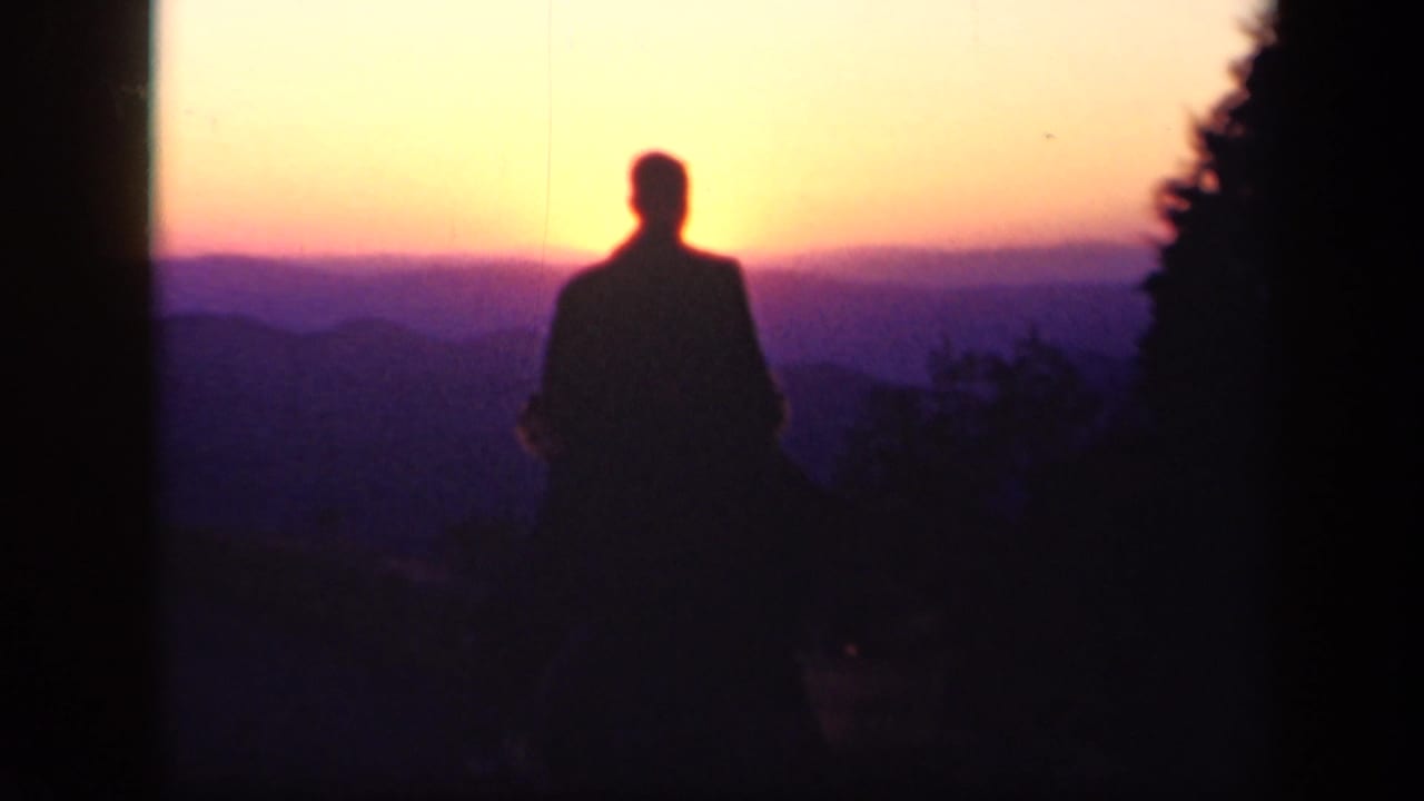 A silhouetted man stands against a vivid sunset over layered mountains near Skyline Drive, Virginia.
