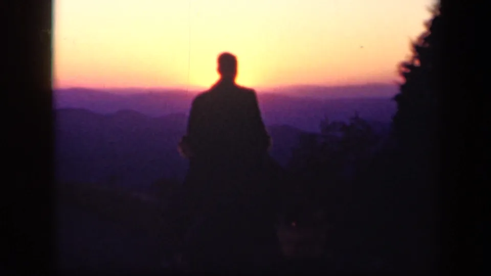 A silhouetted man stands against a vivid sunset over layered mountains near Skyline Drive, Virginia.