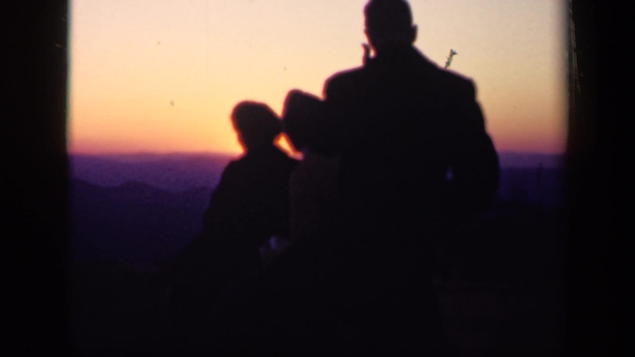 1943 Skyline Drive home-movie frame showing a family group in silhouette against an orange and purple mountain sunset.