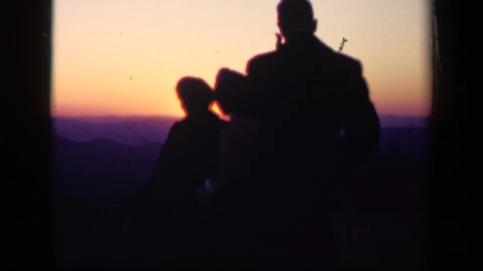 1943 Skyline Drive home-movie frame showing a family group in silhouette against an orange and purple mountain sunset.