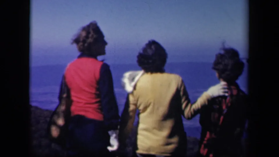 Three women in 1940s-style clothing stand close together at Skyline Drive, looking across a hazy blue landscape from an overlook.