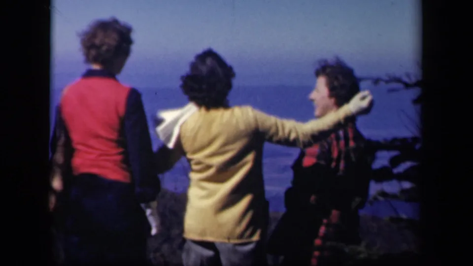 Three women at the Skyline Drive overlook share a relaxed moment, with one reaching an arm around another's shoulder.