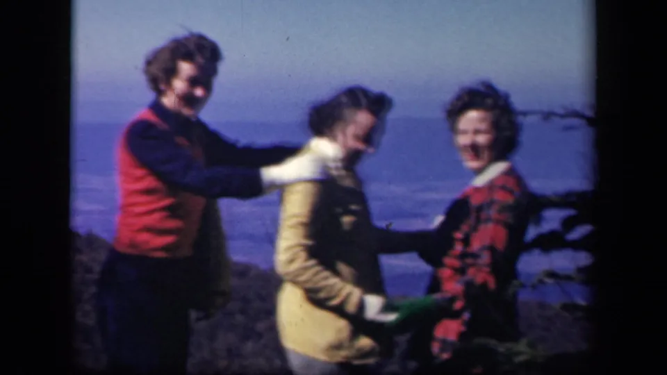 Three adults in 1940s-style winter clothing pose and smile near a rocky overlook at Skyline Drive, Virginia.